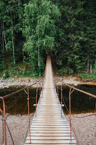 A beautiful suspension bridge over the river flowing in the Olenyi Streams park in the Sverdlovsk region photo