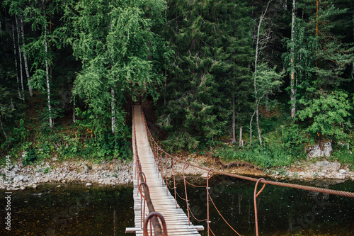 A beautiful suspension bridge over the river flowing in the Olenyi Streams park in the Sverdlovsk region photo