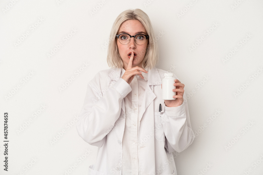 Young pharmacist woman holding pills isolated on white background keeping a secret or asking for silence. Young pharmacist woman holding pills isolated on white background keeping a secret or asking for silence.