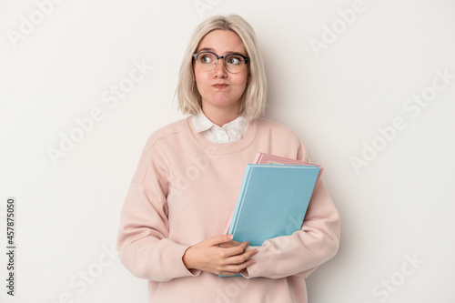 Young caucasian student woman holding books isolated on white background confused, feels doubtful and unsure.