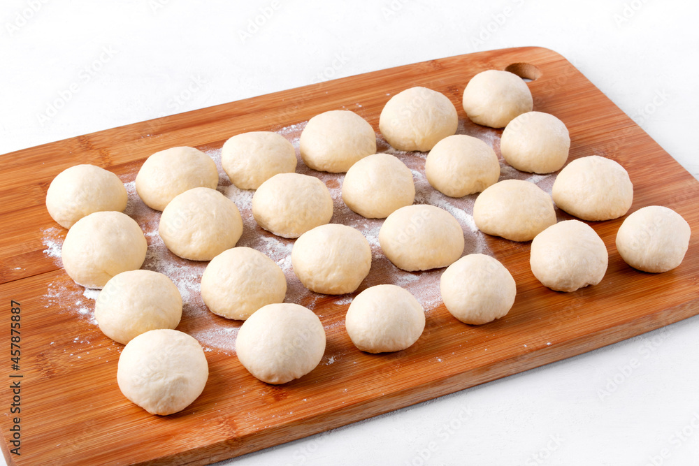 Yeast dough balls on the wooden board with flour. Proofing to bake buns, bread or pizza Yeast dough balls on the wooden board with flour. Proofing to bake buns, bread or pizza