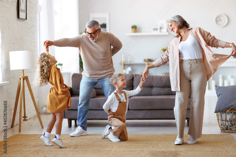 © JenkoAtaman - Active senior grandparents dancing with two happy kids grandchildren in living room © JenkoAtaman - Active senior grandparents dancing with two happy kids grandchildren in living room
