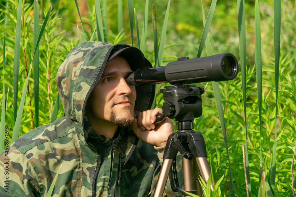 man ornitologist makes observations in the wild with a spotting scope