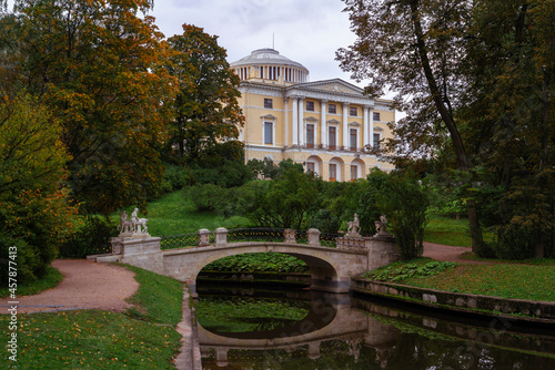 Centaur Bridge over the Slavyanka River in the Pavlovsk Palace and Park Complex against the background of the Pavlovsk Palace on a cloudy autumn day, St. Petersburg, Russia