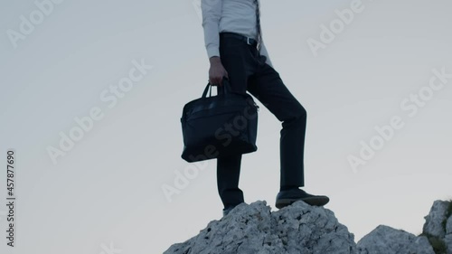 Businessman on top of the rock happy for success.