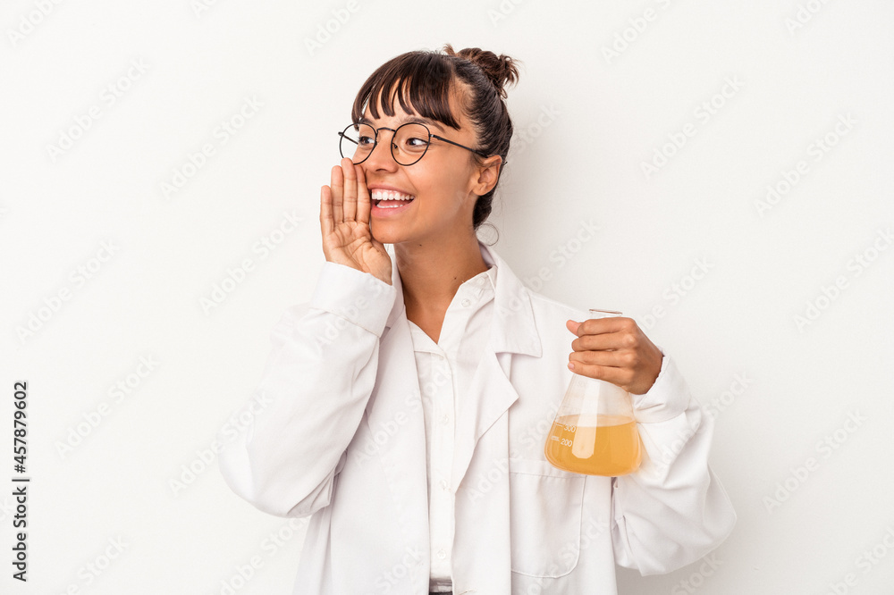Young mixed race scientist woman holding a test tube isolated on white background shouting and holding palm near opened mouth. Young mixed race scientist woman holding a test tube isolated on white background shouting and holding palm near opened mouth.