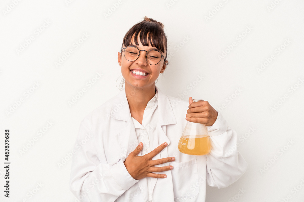 Young mixed race scientist woman holding a test tube isolated on white background laughing and having fun. Young mixed race scientist woman holding a test tube isolated on white background laughing and having fun.