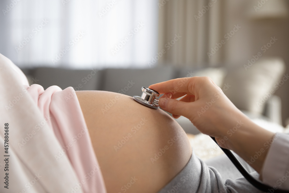 Prenatal health care. Close up of young pregnant woman visiting doctor at  antenatal clinic. Medic gynecologist examine fetal heartbeat rate moving  stethoscope by naked baby bump of expectant mother Photos | Adobe