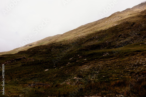 Hill side in Connemara Ireland. A grassy slope in the shade and the top part is sunny. Overcast day, no rain. 