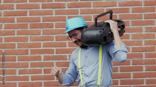 Man with suspenders listens to music with vintage radio.