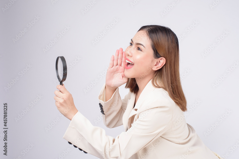 Young beautiful woman in suit holding magnifying glass over white background studio Young beautiful woman in suit holding magnifying glass over white background studio