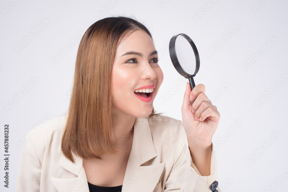 Young beautiful woman in suit holding magnifying glass over white background studio Young beautiful woman in suit holding magnifying glass over white background studio