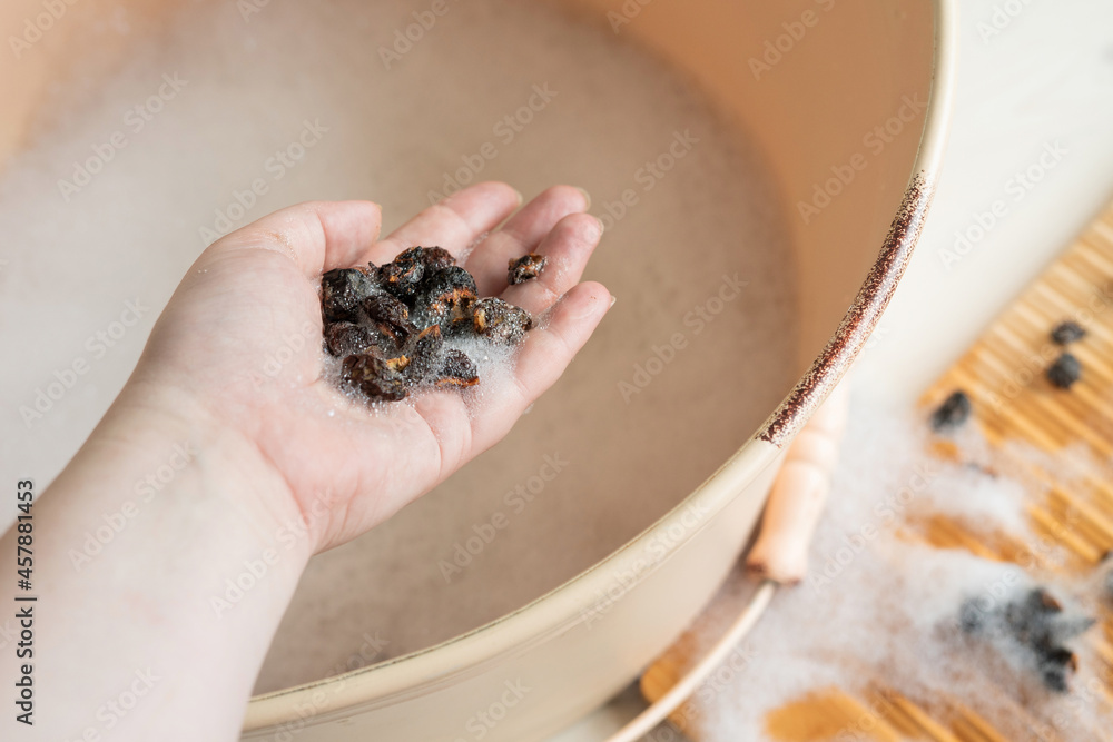 Obraz premium Eco-friendly natural laundry detergent - soap nuts and washboard. Zero waste. A woman's hand holds soap nuts over a wash basin. Handwash.