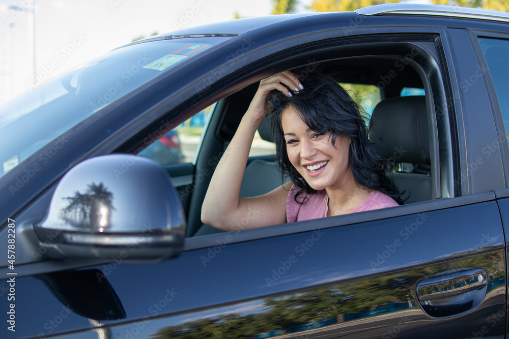 Attractive young woman smiling and driving her car.
