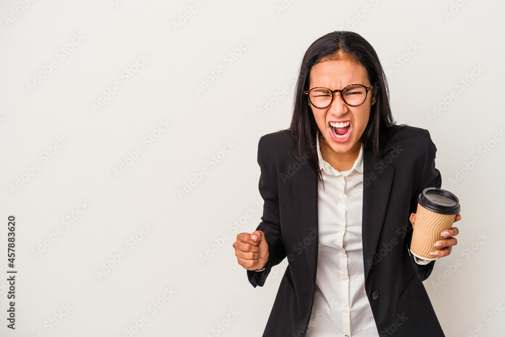 Young business latin woman holding a take away coffee isolated on white background screaming very angry and aggressive. Young business latin woman holding a take away coffee isolated on white background screaming very angry and aggressive.