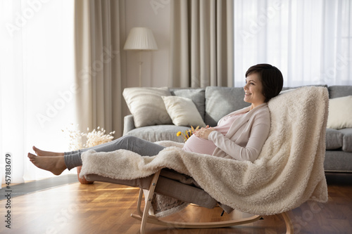 Wanted child. Peaceful young woman expecting mother recline barefoot on comfy rocking chair meditate enjoy sweet moments of pregnancy. Happy future mum relax at light luxury apartment feel pleasure
