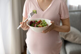 Healthy nutrition in pregnancy. Close up of woman expecting baby eating fresh salad promote preparing vegetable food from natural ingredients. Young future mom recommend dietary vitamin dish for snack