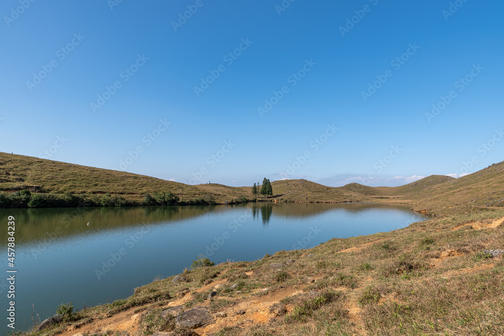 Under the blue sky, the natural lake on the meadow has yellow grass and blue water Under the blue sky, the natural lake on the meadow has yellow grass and blue water