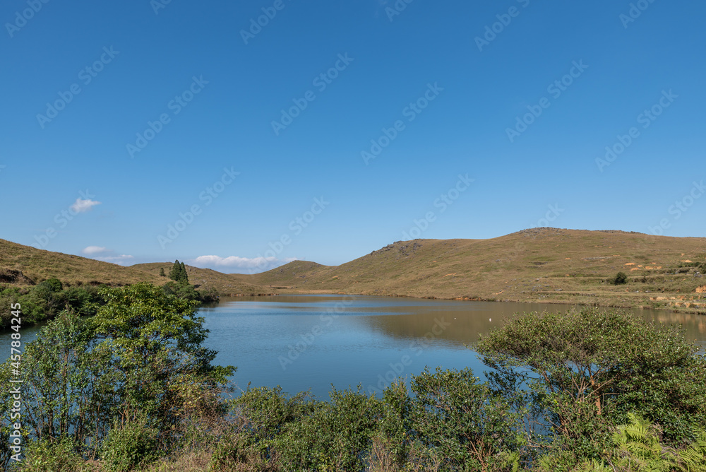 Under the blue sky, the natural lake on the meadow has yellow grass and blue water Under the blue sky, the natural lake on the meadow has yellow grass and blue water