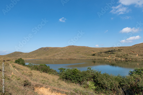 Under the blue sky, the natural lake on the meadow has yellow grass and blue water