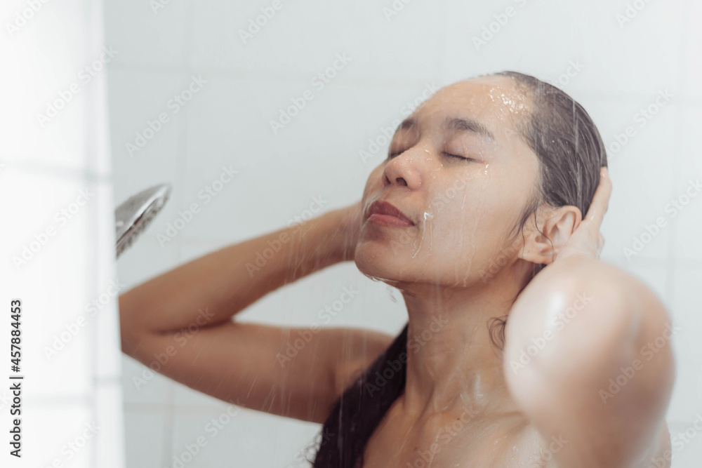 Naklejka premium Young woman washing hair in shower. Asian woman washing her black hair.