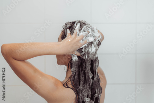 Young woman washing hair in shower. Asian woman washing her black hair.