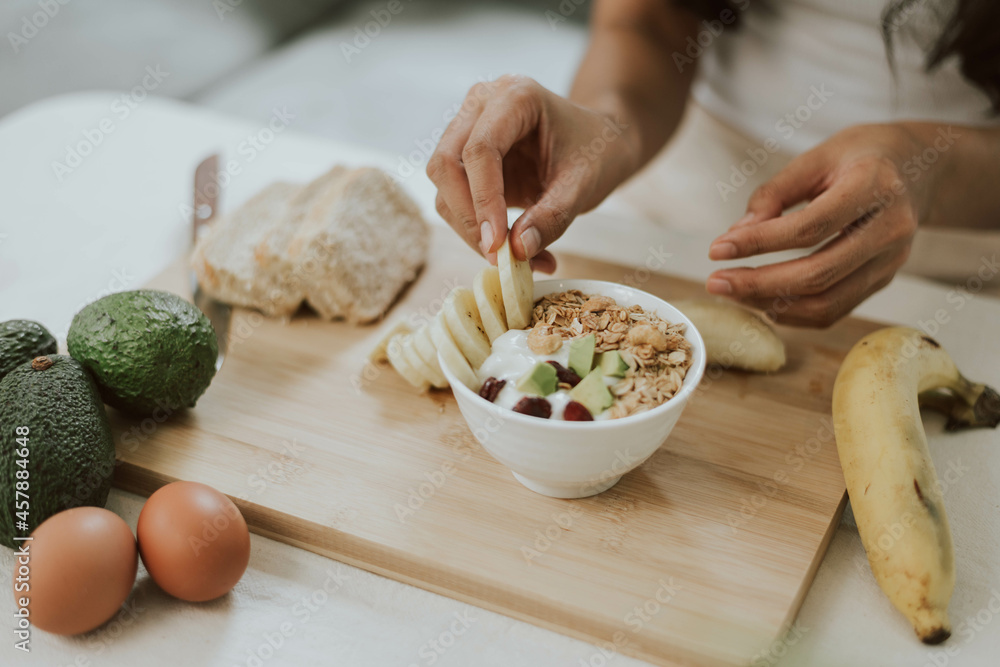 Close up of woman hands holding granola flakes in bowl. Young woman cooking healthy food at home. Healthy and wellness concept. Close up of woman hands holding granola flakes in bowl. Young woman cooking healthy food at home. Healthy and wellness concept.