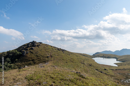 The full view of the natural lake on the grassland, with blue sky, clear water and yellow grass