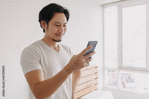 Happy and smile face of Asian man using smartphone.