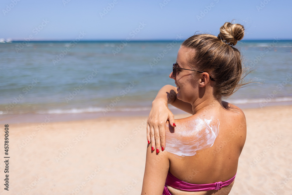 Sunbath protection. Woman using sun cream on the beach. Sun on a girl's shoulder, Sun-shaped cream on a young woman's skin. girl on the beach, woman on the sea.. Sunbath protection. Woman using sun cream on the beach. Sun on a girl's shoulder, Sun-shaped cream on a young woman's skin. girl on the beach, woman on the sea..