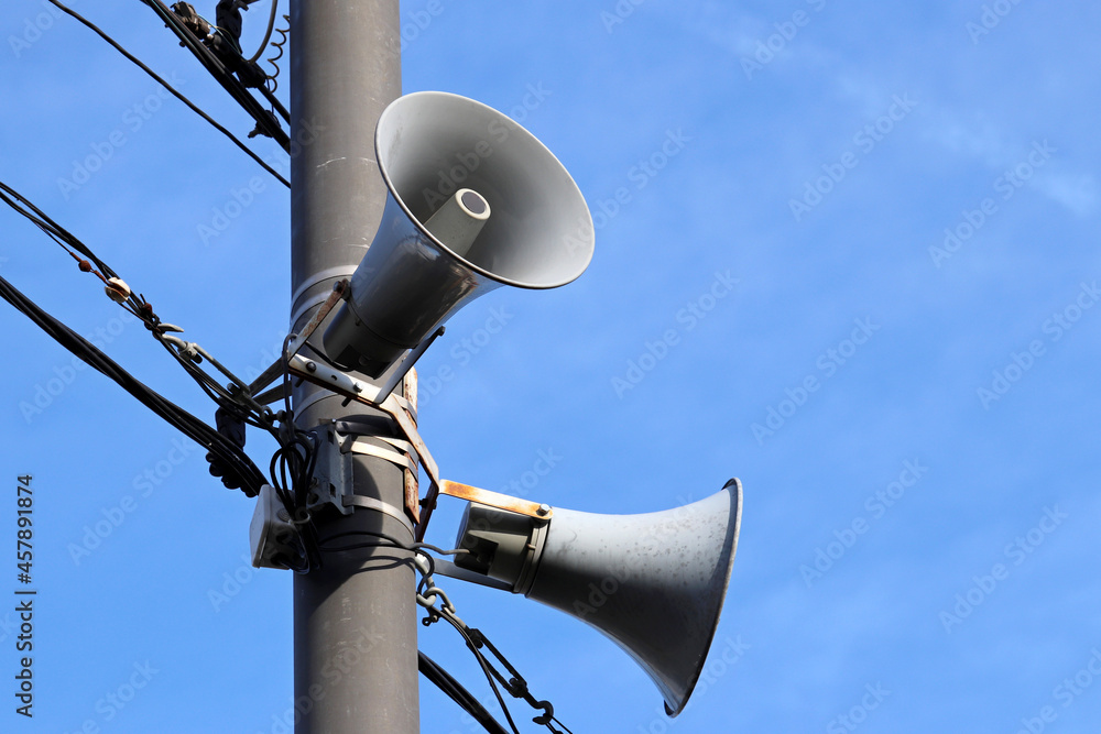 Loudspeakers on pole, two public address system speakers on blue sky background Loudspeakers on pole, two public address system speakers on blue sky background