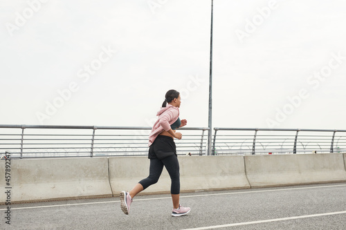 Rear view of young athlete running in the morning along the road on fresh air