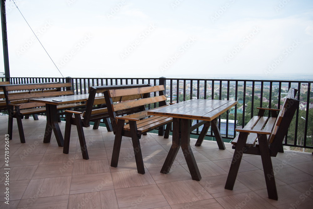 An empty terrace of a summer cafe. Great view, in the distance the sea. Empty tables