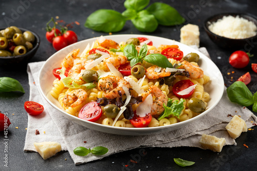 King prawn pasta salad with marinated green olives, cherry tomatoes and parmesan cheese shavings. Healthy food.