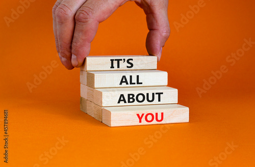 It is all about you symbol. Wooden blocks with words 'It is all about you'. Beautiful orange background. Businessman hand. Copy space. Business and it is all about you concept. photo