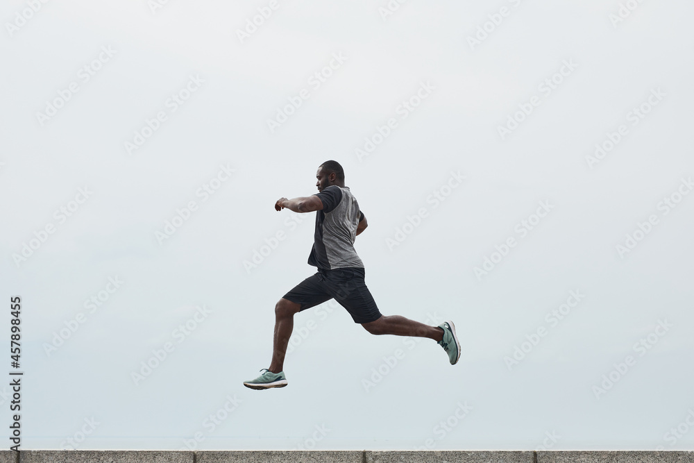 African young man exercising outdoors, he jumping over a barrier