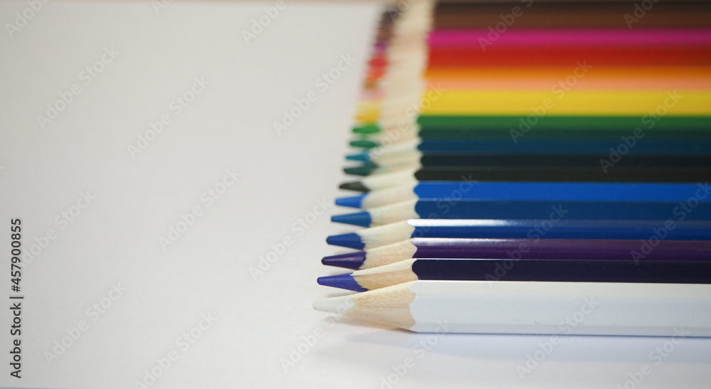 Obraz premium Colored pencils lie in a row on a white background with blur