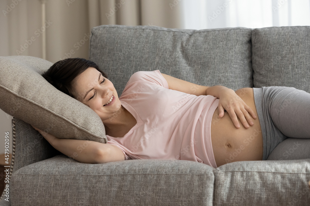 Good dream. Smiling millennial mother to be enjoy nap at midday on soft cozy couch. Healthy woman expecting baby relax on comfortable sofa caress embrace belly breath fresh air has pleasant daily rest Good dream. Smiling millennial mother to be enjoy nap at midday on soft cozy couch. Healthy woman expecting baby relax on comfortable sofa caress embrace belly breath fresh air has pleasant daily rest