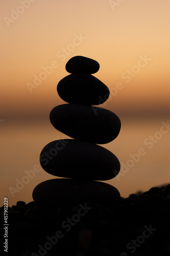 Pebble tower on the seaside at sunset. Pyramid of stones. Balanced zen stones.