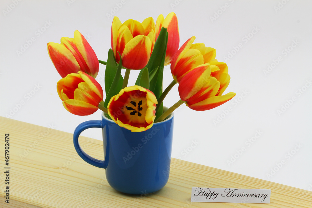 Happy Anniversary card with colorful Dutch tulips in blue mug on wooden surface