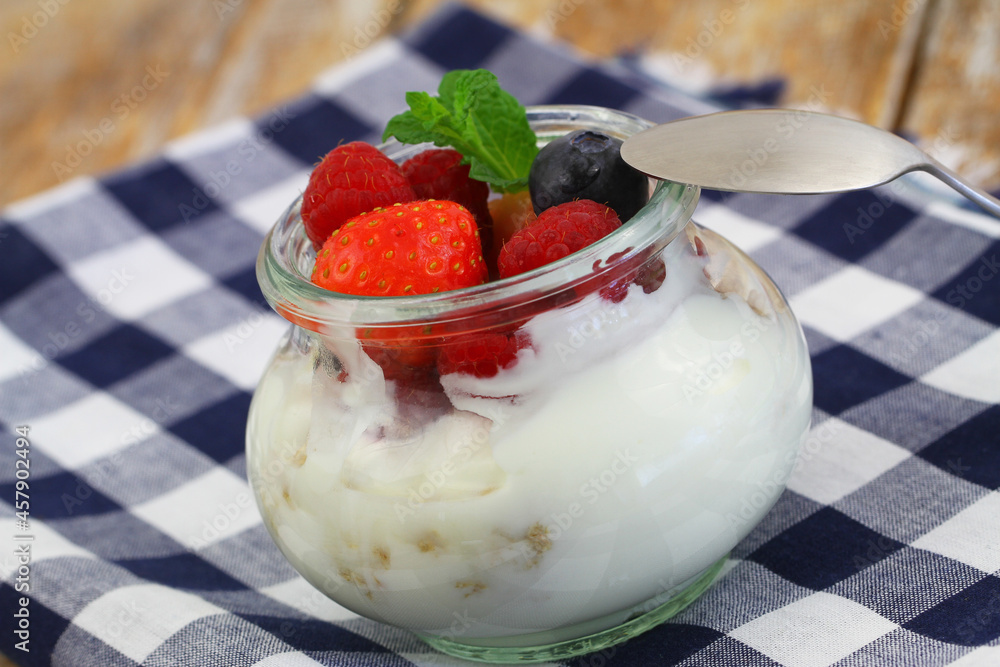 Healthy breakfast: bio yoghurt with granola, fresh strawberries, raspberries and blueberries in transparent glass