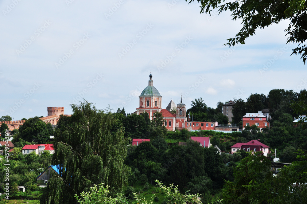 Panoramic view of the city. View of the old church and the fortress wall. Private houses among the trees.