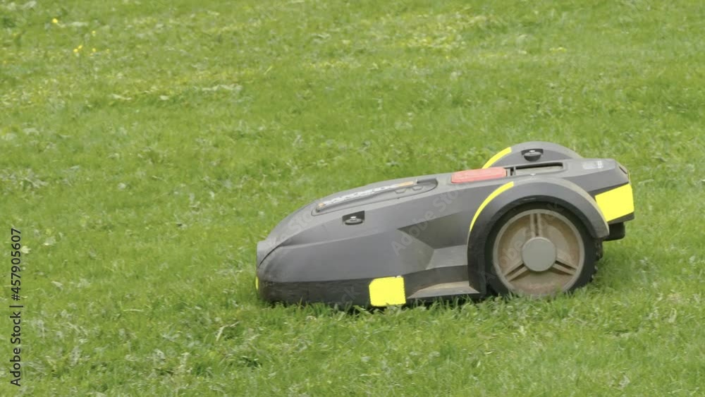 The black car lawn mower on the grass moving slowly on the lawn in Estonia The black car lawn mower on the grass moving slowly on the lawn in Estonia