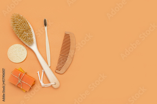Bathroom accessories with zero waste, natural bristle brush, wooden toothbrush, bars of solid soap, wooden comb, with a palm leaf on a beige background