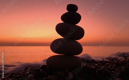 Pebble tower on the seaside at sunset. Pyramid of stones. Balanced zen stones.