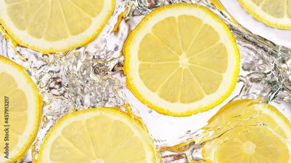 Super Slow Motion Shot of Splashing Fresh Lemon Slices into Water on White Background at 1000 fps. Super Slow Motion Shot of Splashing Fresh Lemon Slices into Water on White Background at 1000 fps.
