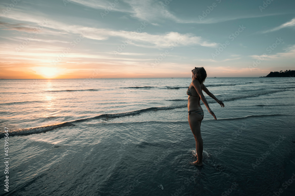 A woman sees off the sun on a tropical island dreaming beach.