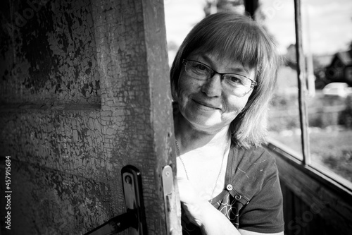 Obraz na plátně A middle-aged woman looks out the door of a house in the village