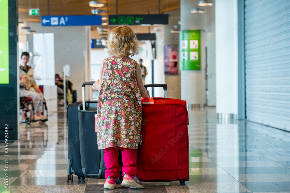 Cute blonde girl with travel luggage at the airport.