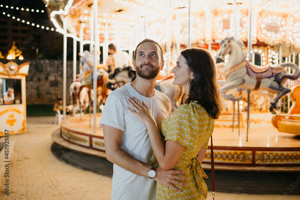 A young woman in a dress and her boyfriend who are staying near the carousel. A young woman in a dress and her boyfriend who are staying near the carousel.